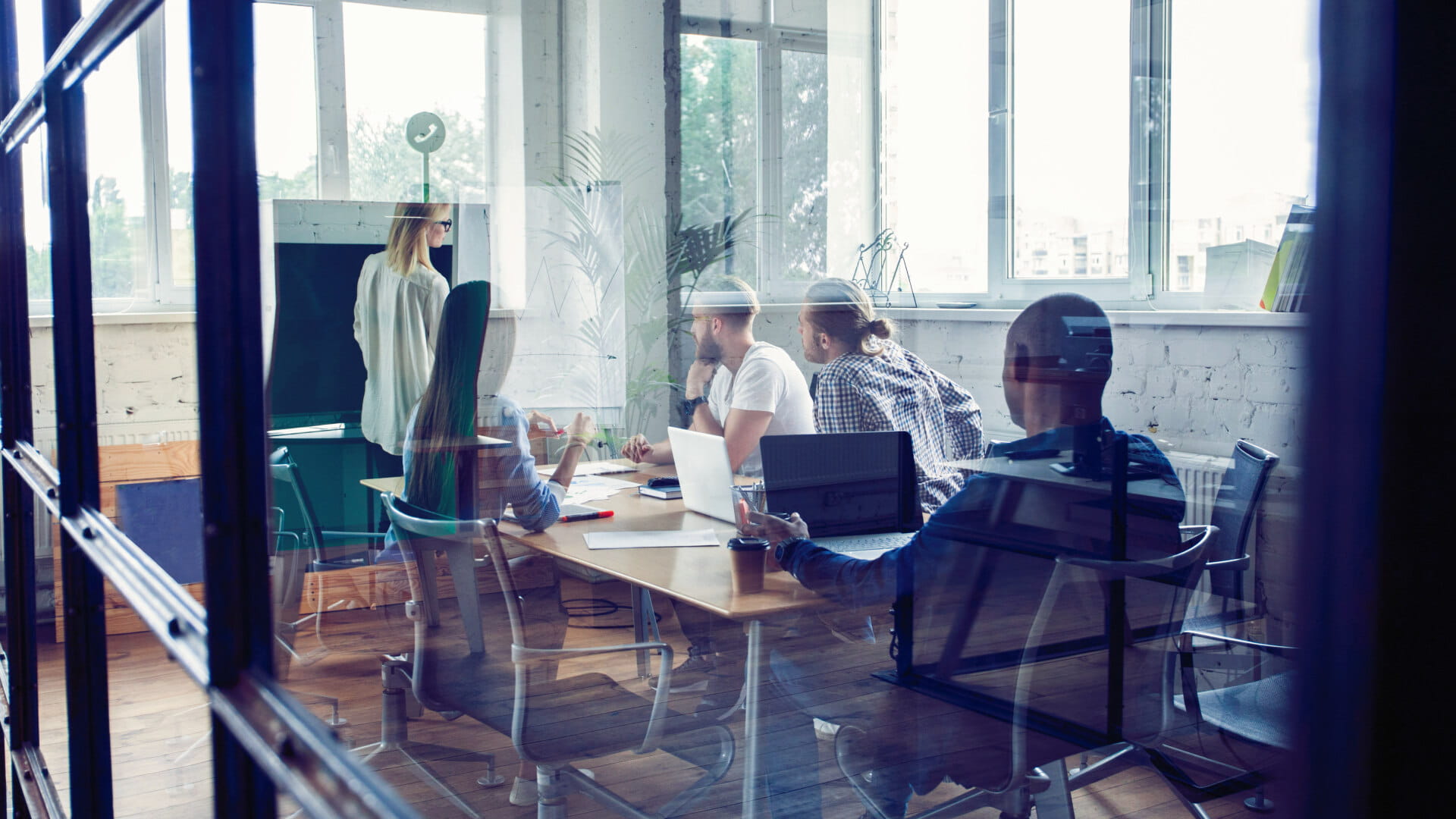 Professionals collaborating during a meeting in a modern glass-walled office.