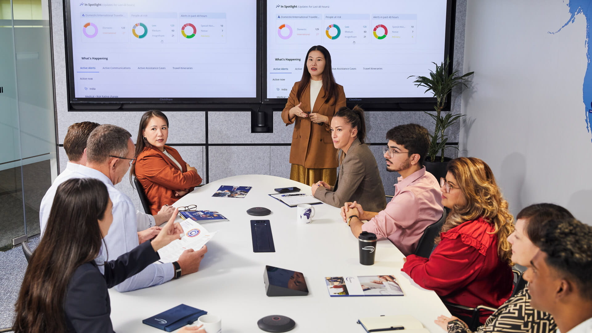 Professionals collaborating in a meeting with operational monitoring dashboards displayed on screens.