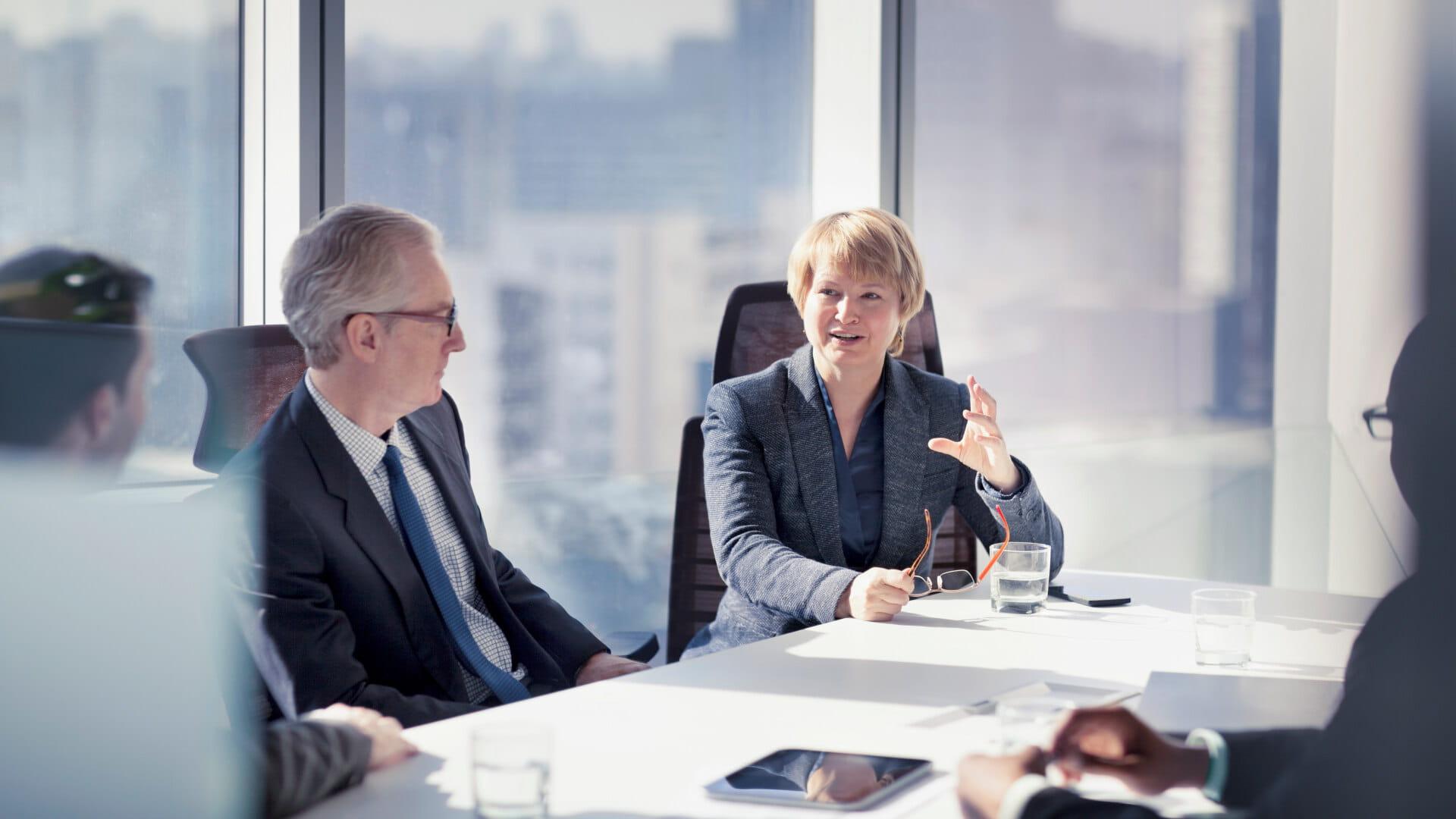 Mature adult businesswoman leader boss CEO executive with group of business people sitting together in conference meeting room.