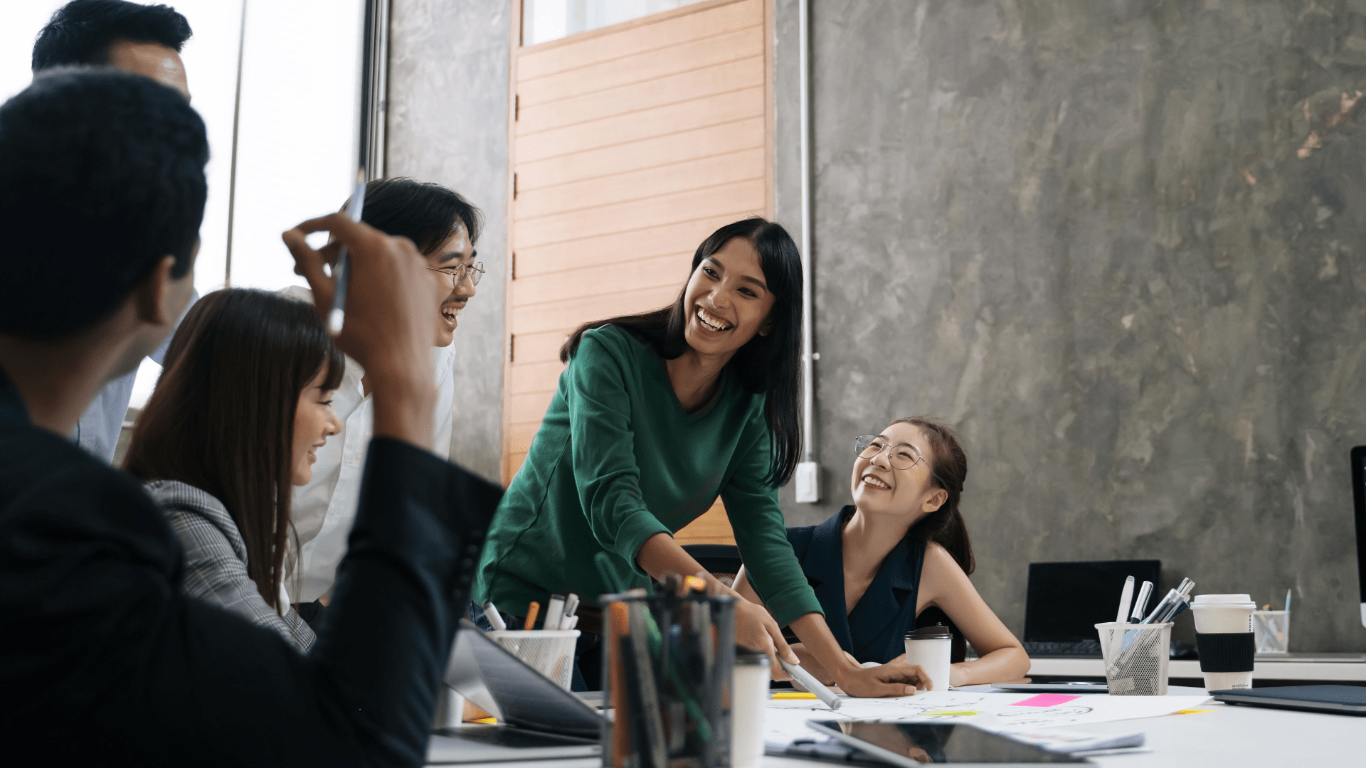 Image of male and female employees in a meeting room chatting and smiling 